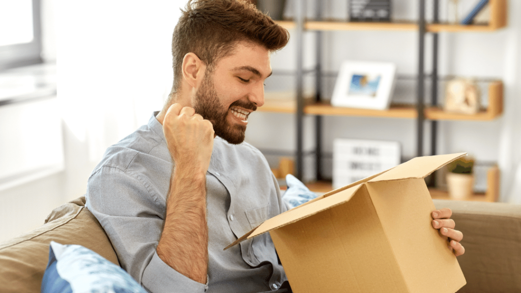 man with fist pump looking happy and excited as he opens his corrugated box